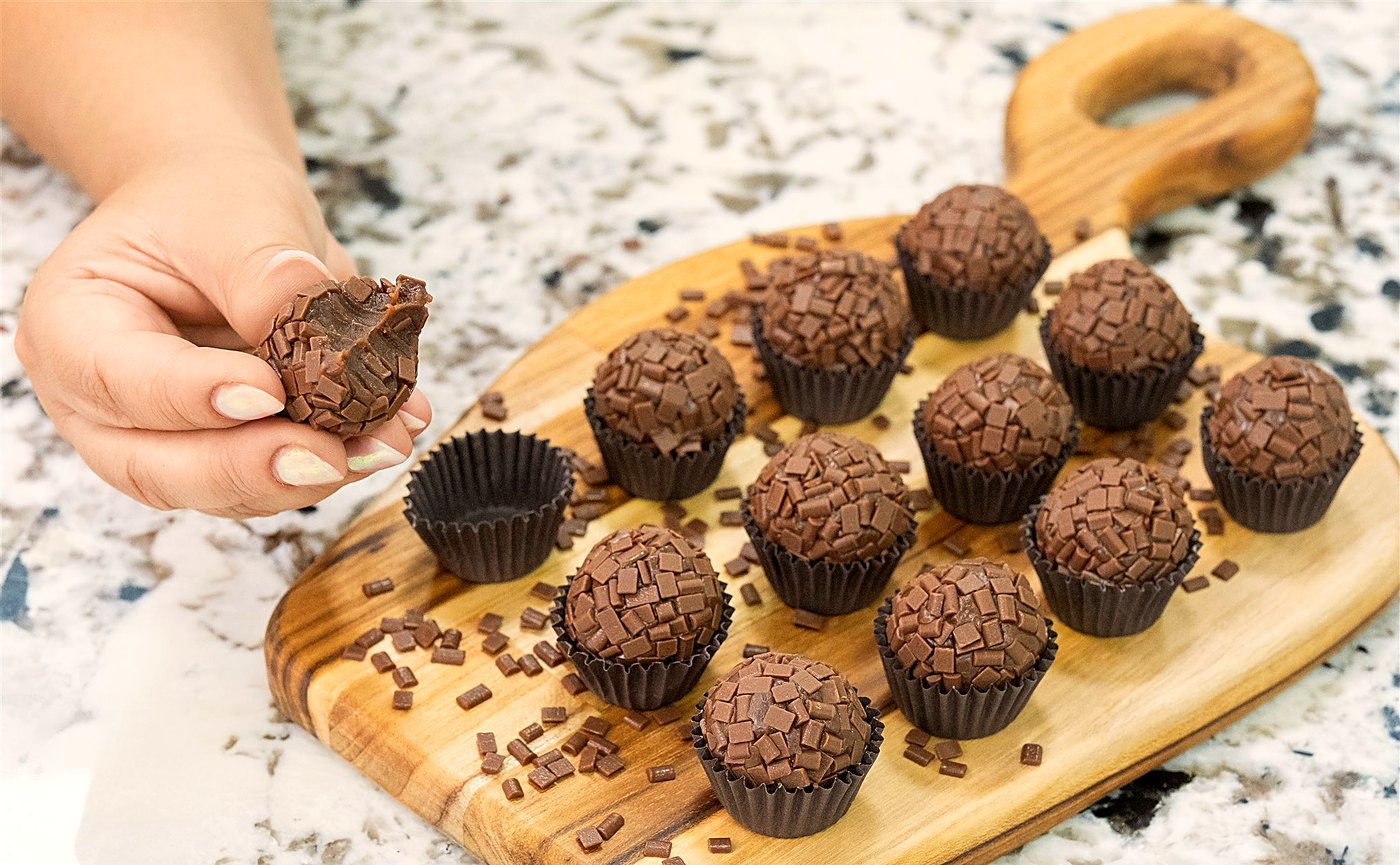 Mão retirando um brigadeiro da tábua